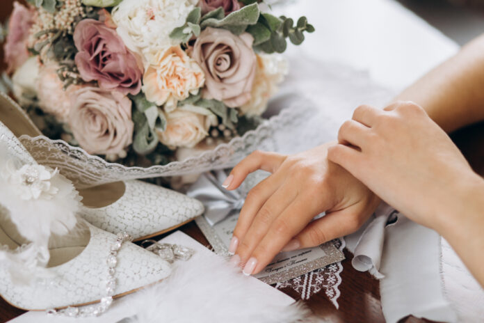 Bride puts her hands on the table near floral bouquet, shoes and